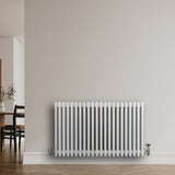 Radiador tradicional de 4 colunas, acabamento branco, instalado na parede, com válvulas visíveis e design elegante e funcional