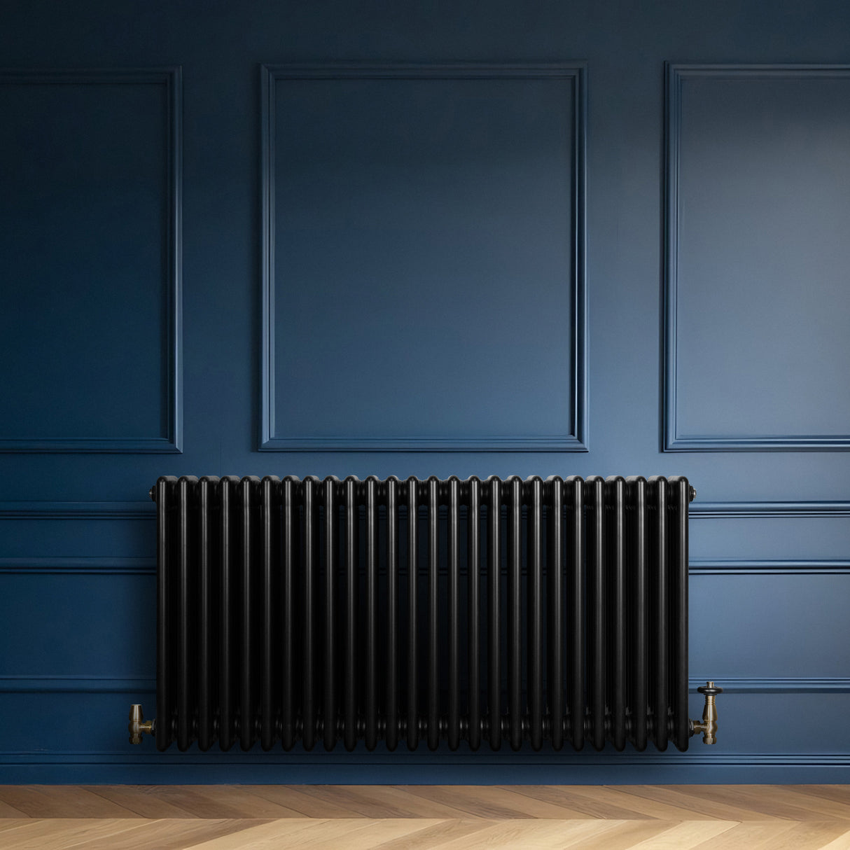 Radiador tradicional de 4 colunas, acabamento preto brilhante, instalado em parede azul, com válvulas de metal dourado visíveis