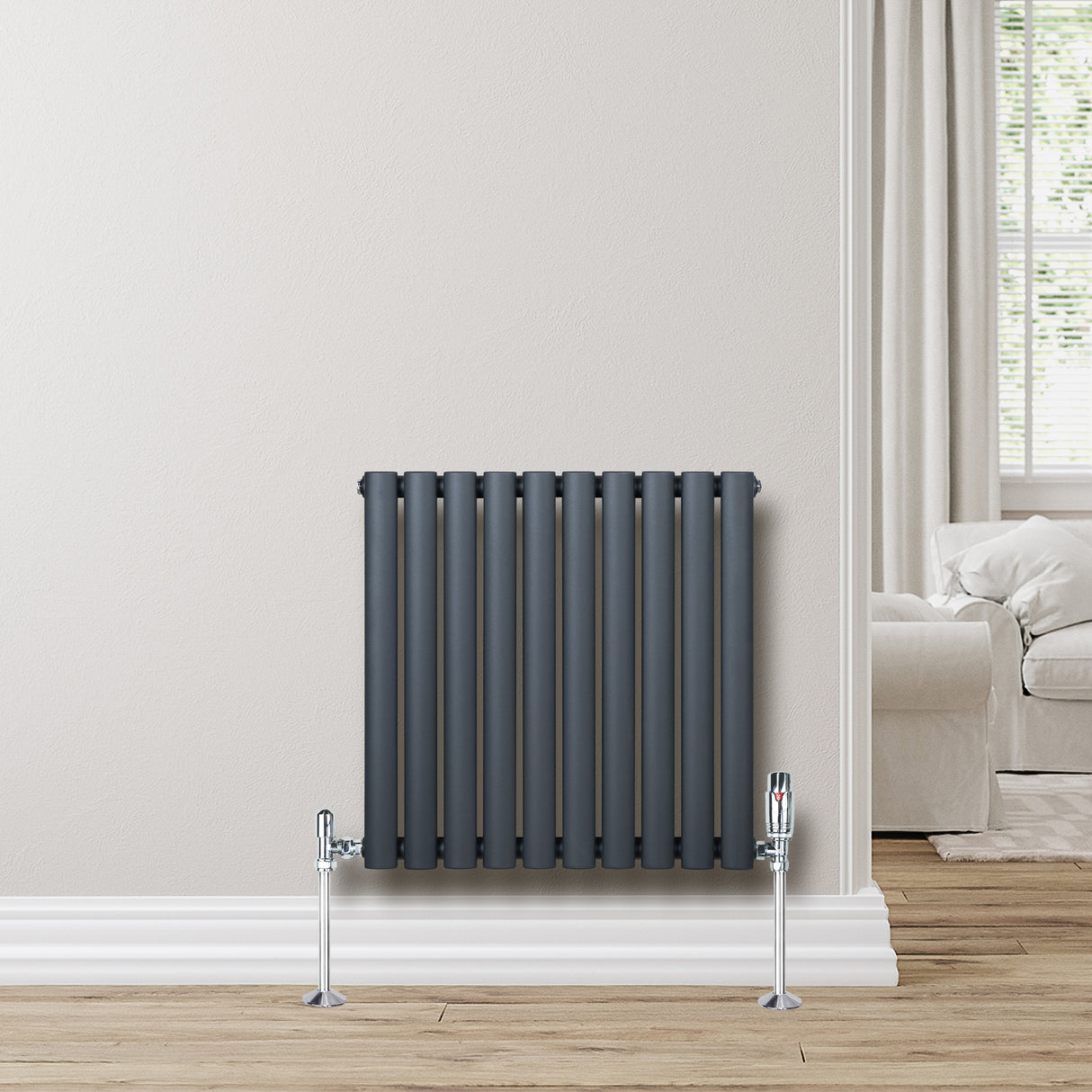 Radiador de coluna simples oval cinza antracite, com válvulas, instalado em parede clara, em ambiente moderno e aconchegante