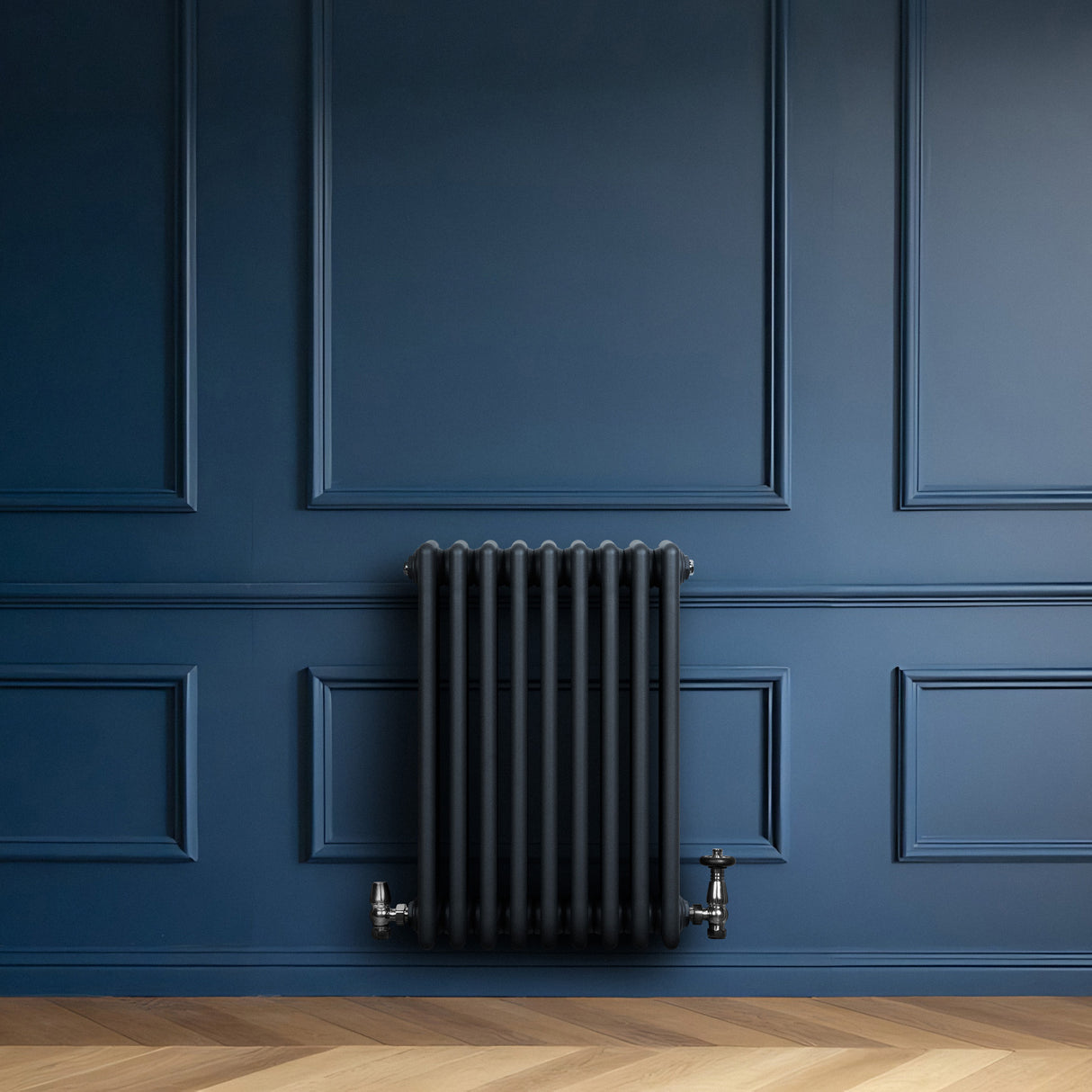 Radiador tradicional de 4 colunas em cinza antracite, instalado em uma parede azul escura, com detalhes elegantes e acabamento liso