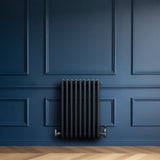 Radiador tradicional de 4 colunas em cinza antracite, instalado em uma parede azul escura, com detalhes elegantes e acabamento liso