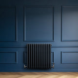 Radiador tradicional de 4 colunas em cinza antracite, instalado em parede azul escura, com textura lisa e design clássico