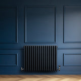 Radiador tradicional de 4 colunas em cinza antracite, com válvulas, instalado em parede azul, destacando seu design elegante e moderno