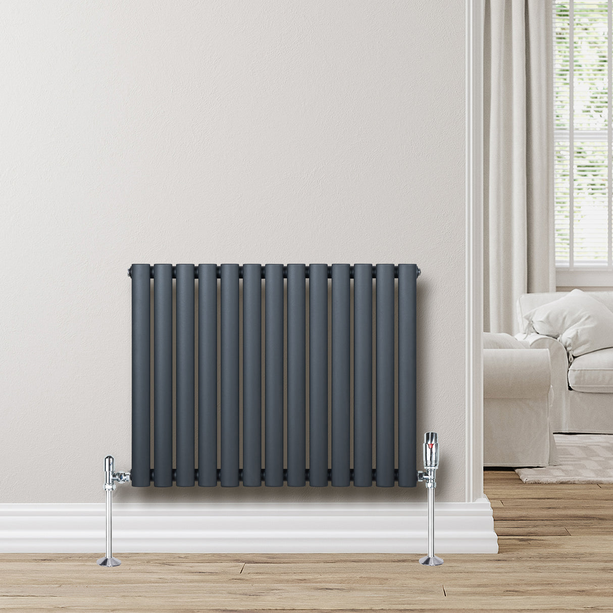 Radiador de coluna oval cinza antracite, com tubos verticais e suportes cromados, instalado em parede clara, ambiente moderno e aconchegante