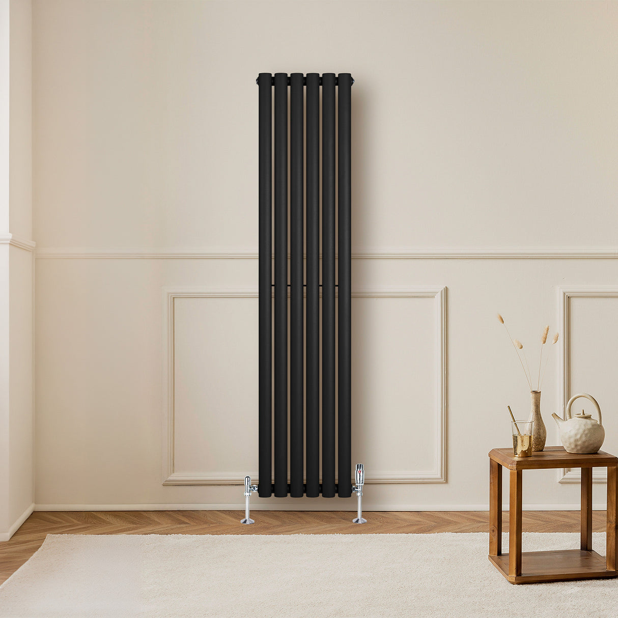 Radiador de coluna simples oval preto, com seis tubos verticais, instalado em parede clara, ao lado de mesa de madeira e decoração minimalista