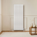 Radiador de coluna simples oval branco, 1600 mm x 600 mm, com acabamento liso e moderno, instalado em parede clara, ao lado de mesa de madeira